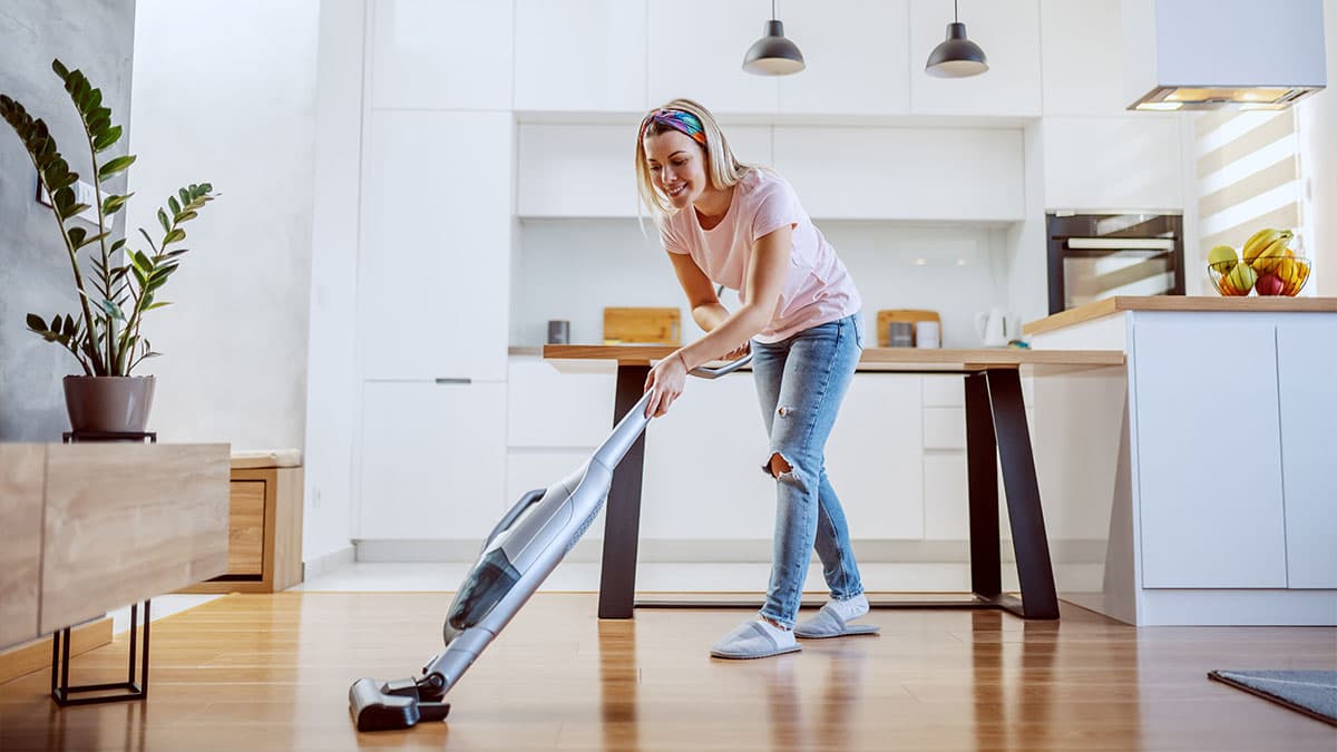 Woman vacuuming a bright kitchen and dining area while preparing a Mercer Island home for guests.