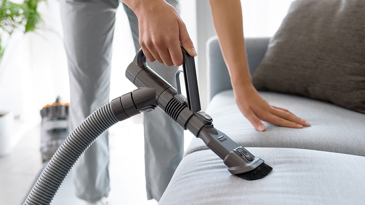 Vacuuming dust from sofa upholstery during deep cleaning in a Kent, WA