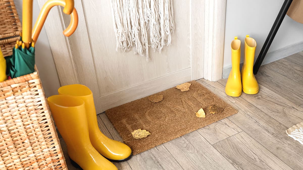 Yellow rain boots and fallen leaves at a home entryway during fall